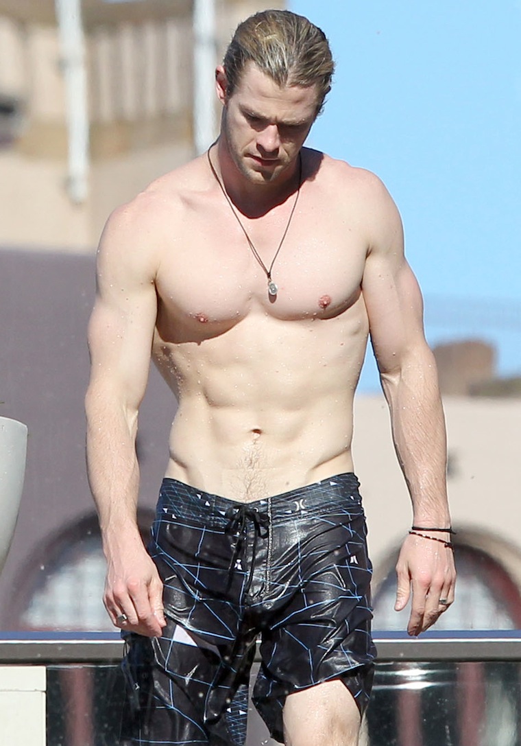 Chris Hemsworth shows off his ripped body as he chills by his hotel pool.